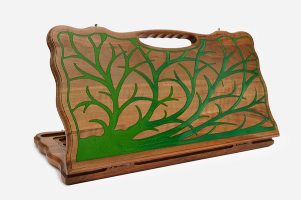 Folding walnut backgammon board with a green epoxy tree of life design and a cut-out carry handle, standing upright