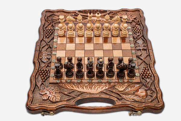 Folding walnut chess board carved with pomegranate and grape-vine motifs and beech and walnut pieces set up for play