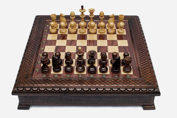 Wooden chess set in dark walnut with a carved lattice and beaded border and Staunton pieces set up for play