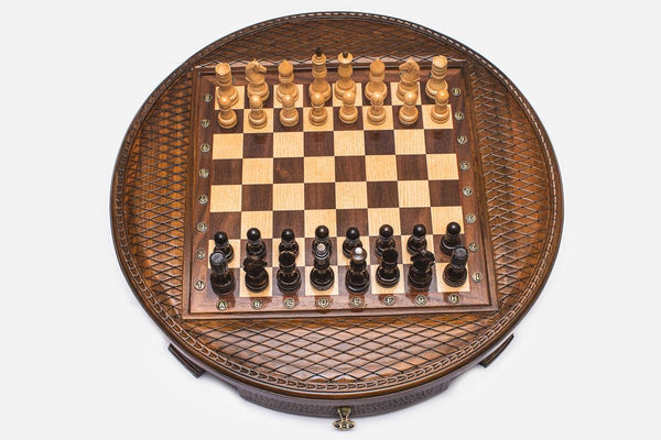 Round wooden chess set with woven lattice-carved border and Staunton pieces set up on the inlaid board