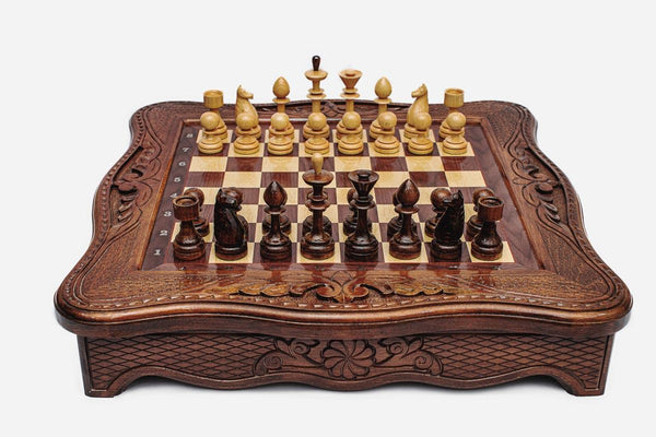 Handmade wooden chess set with carved scalloped frame and Staunton pieces arranged on the walnut and maple board