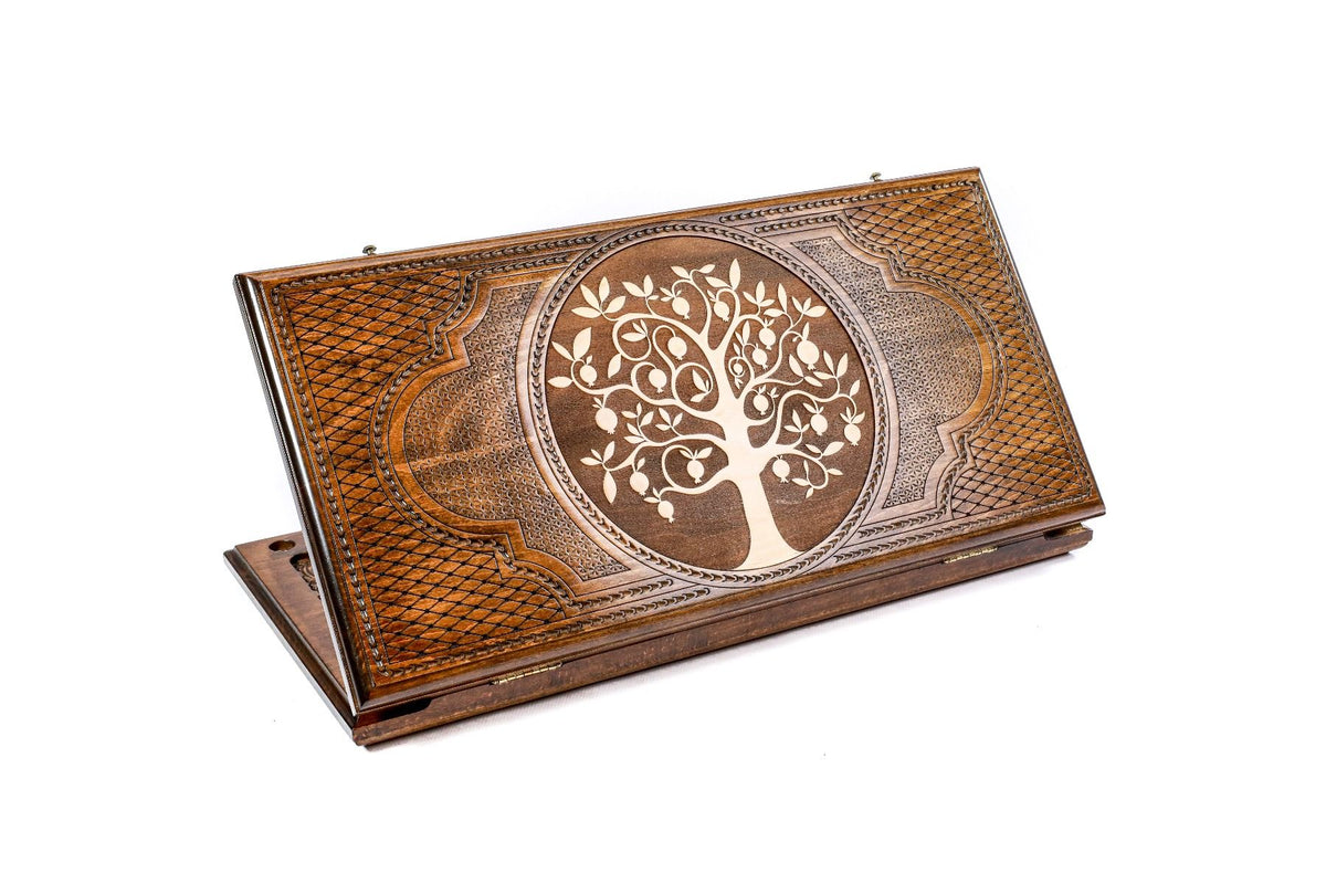 A hand-carved wooden backgammon board with a tree of life design carved on the lid