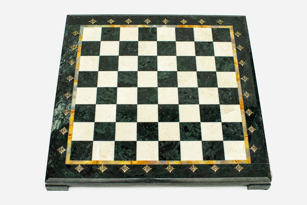 Top-down view of the empty green and cream marble chess board with an amber onyx inlay and brass medallions