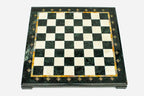 Top-down view of the empty green and cream marble chess board with an amber onyx inlay and brass medallions