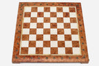 Top-down view of the empty coral and cream marble chess board with brass coordinate medallions