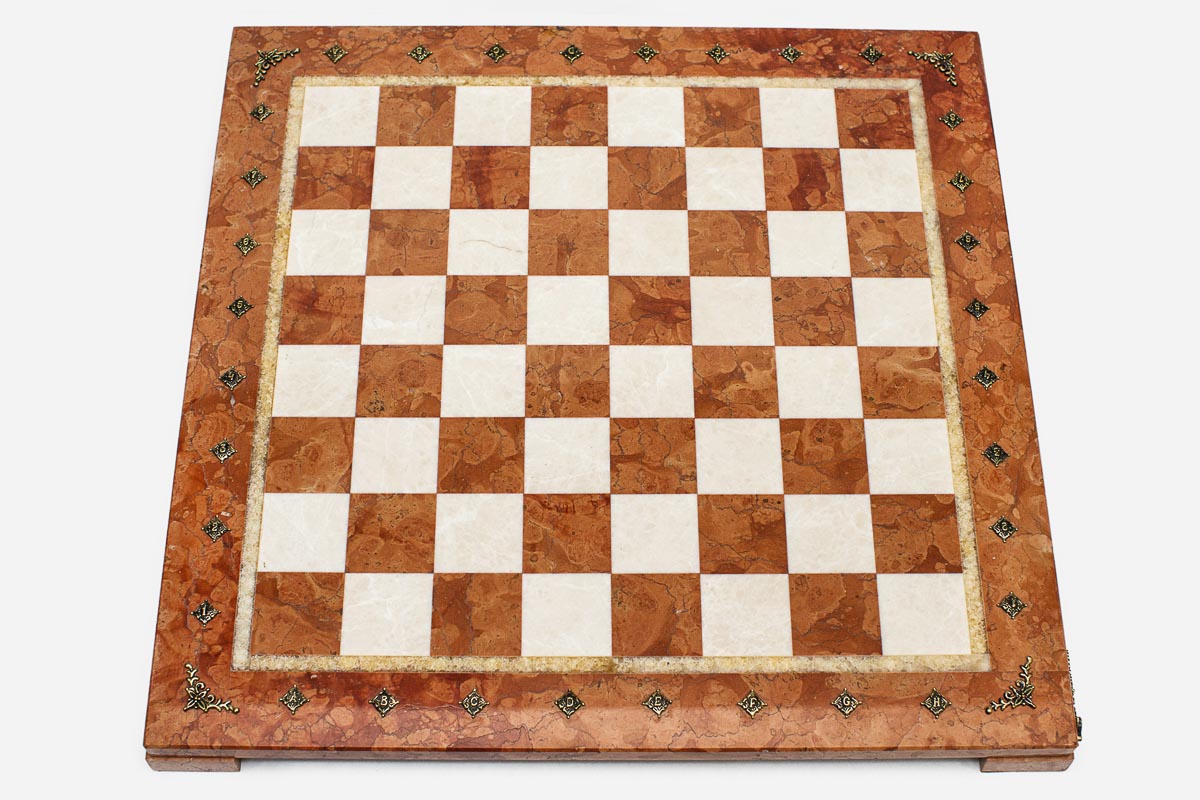 Top-down view of the empty coral and cream marble chess board with brass coordinate medallions