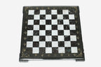 Top-down view of the empty burgundy and white marble chess board with a grey border and brass coordinate medallions