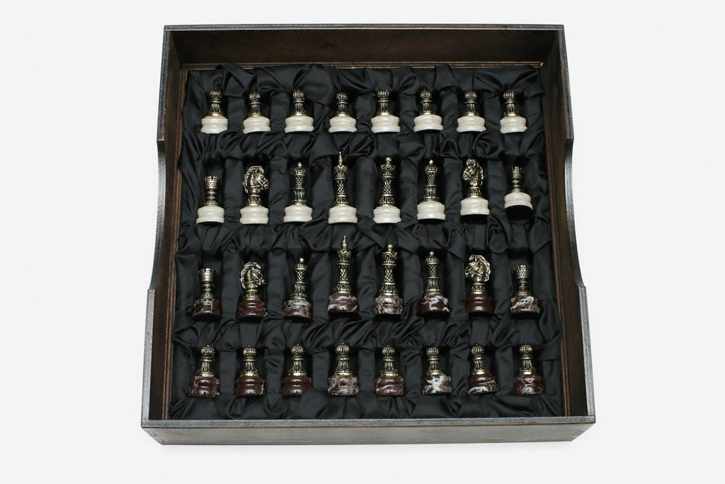 Bronze chess pieces with marble bases arranged in the black satin-lined wooden box