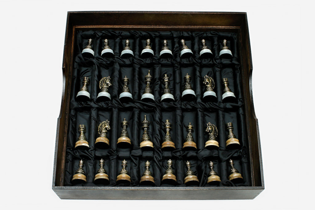 Cast bronze chess pieces on the golden and white marble board