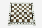 Top-down view of the empty cream and brown marble chess board with brass coordinate medallions