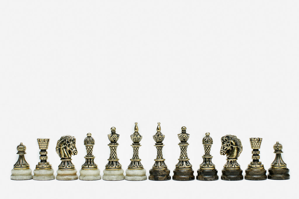 Row of the two-tone bronze chess pieces on marble bases, showing kings, queens, bishops and horse-head knights