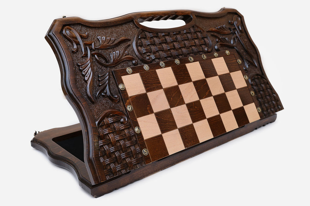 Large carved folding chess board standing open, showing the chessboard, basket-weave and foliate carving and carry-handle cutout