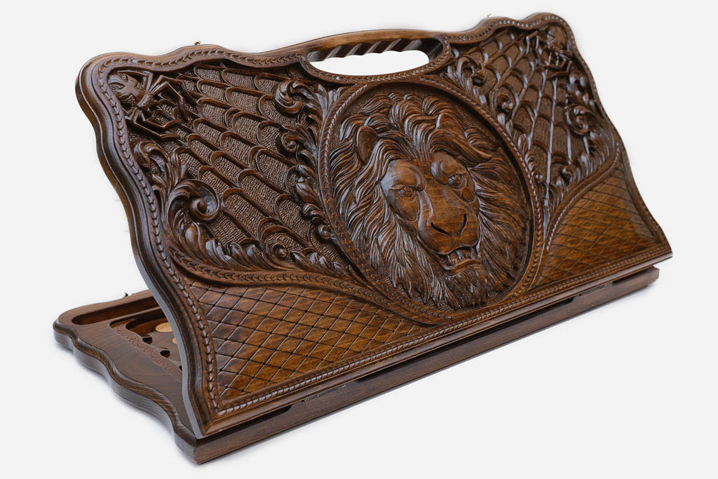 Carved beechwood backgammon board with a lion medallion and spider webs, with a carry handle, propped open