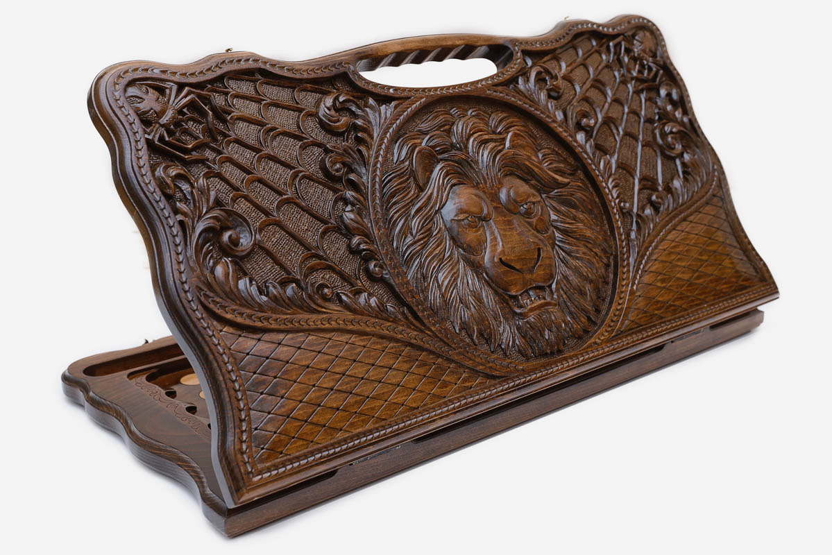 Carved beechwood backgammon board with a lion medallion and spider webs, with a carry handle, propped open
