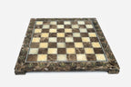 Elevated angle of the polished brown marble chessboard with its brass-studded border