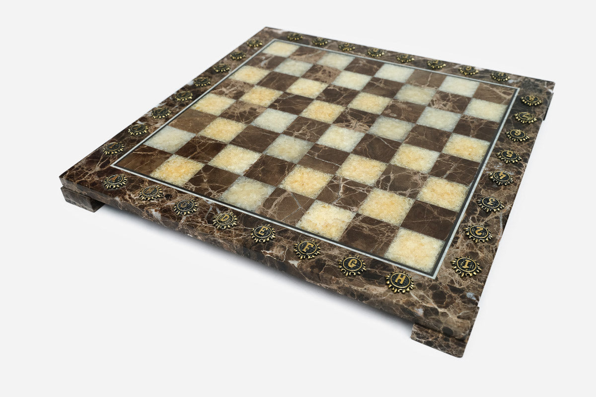 Angled view of the empty brown and cream marble chess board with brass medallions