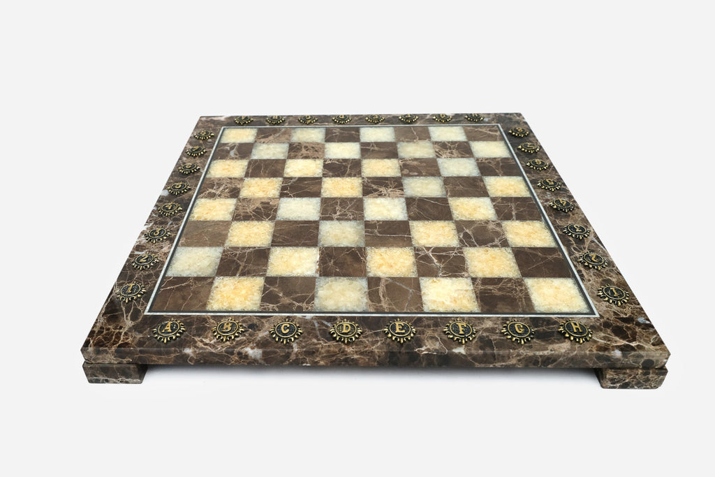 Front view of the brown marble chess board framed by brass letter and number medallions