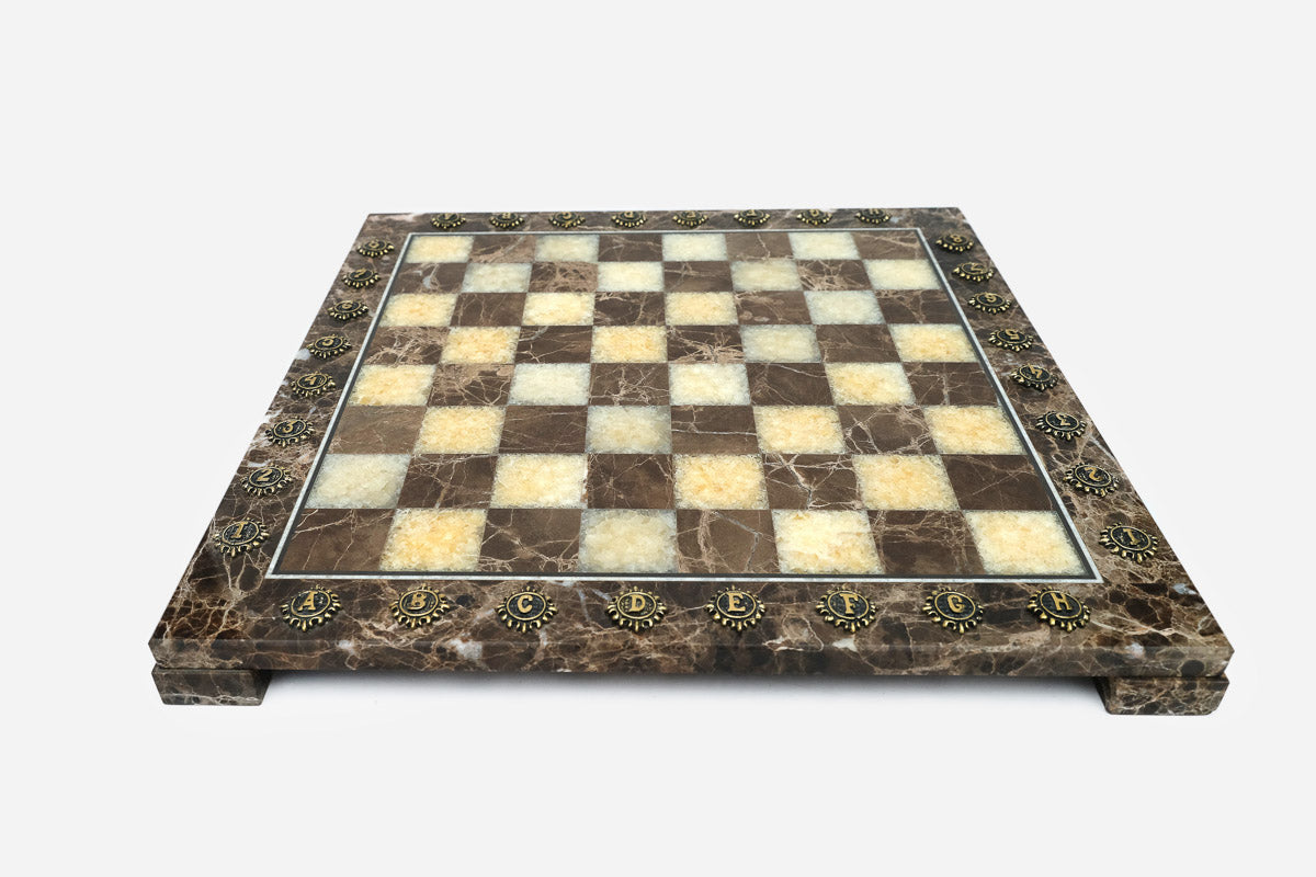Front view of the brown marble chess board framed by brass letter and number medallions