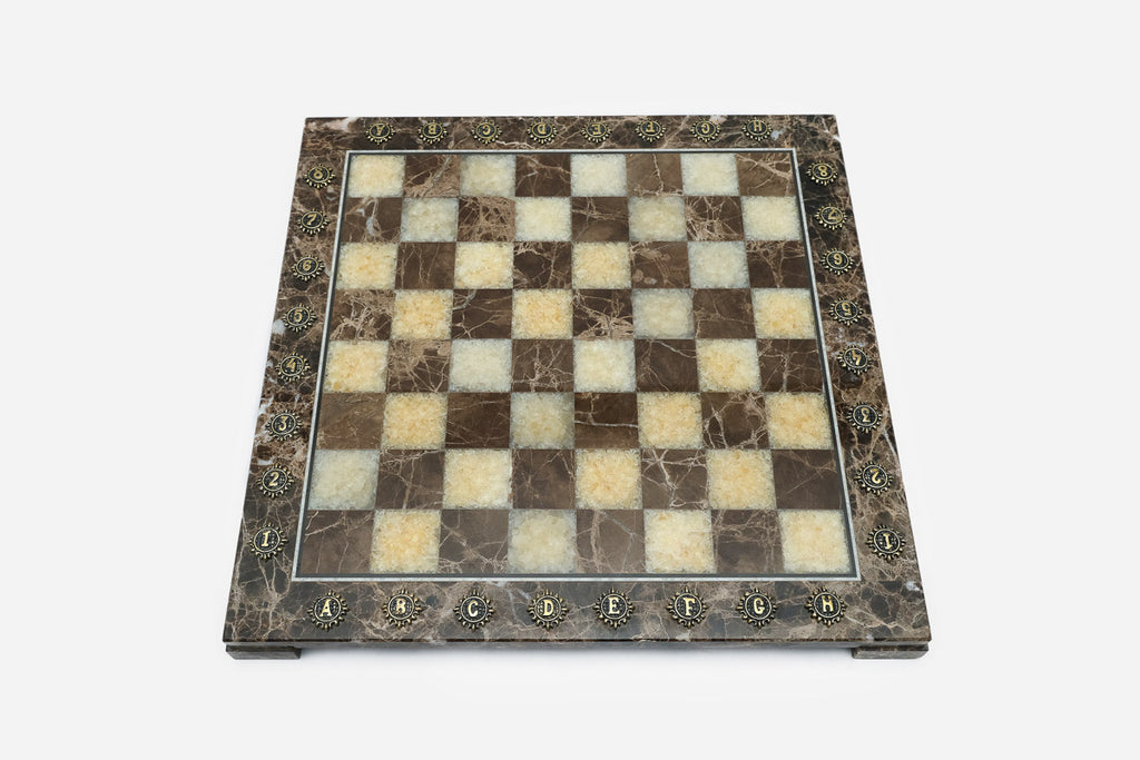 Top-down view of the empty brown and cream marble chess board with brass coordinate medallions