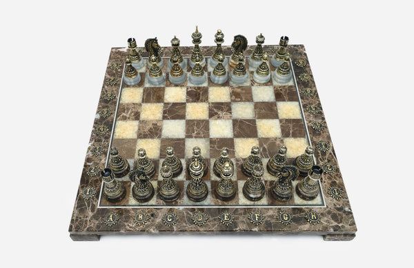 Brown marble chess set with hand-cast bronze pieces arranged for play and brass coordinate medallions