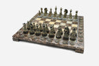 Angled view of the brown marble chess board with detailed bronze pieces set up for play