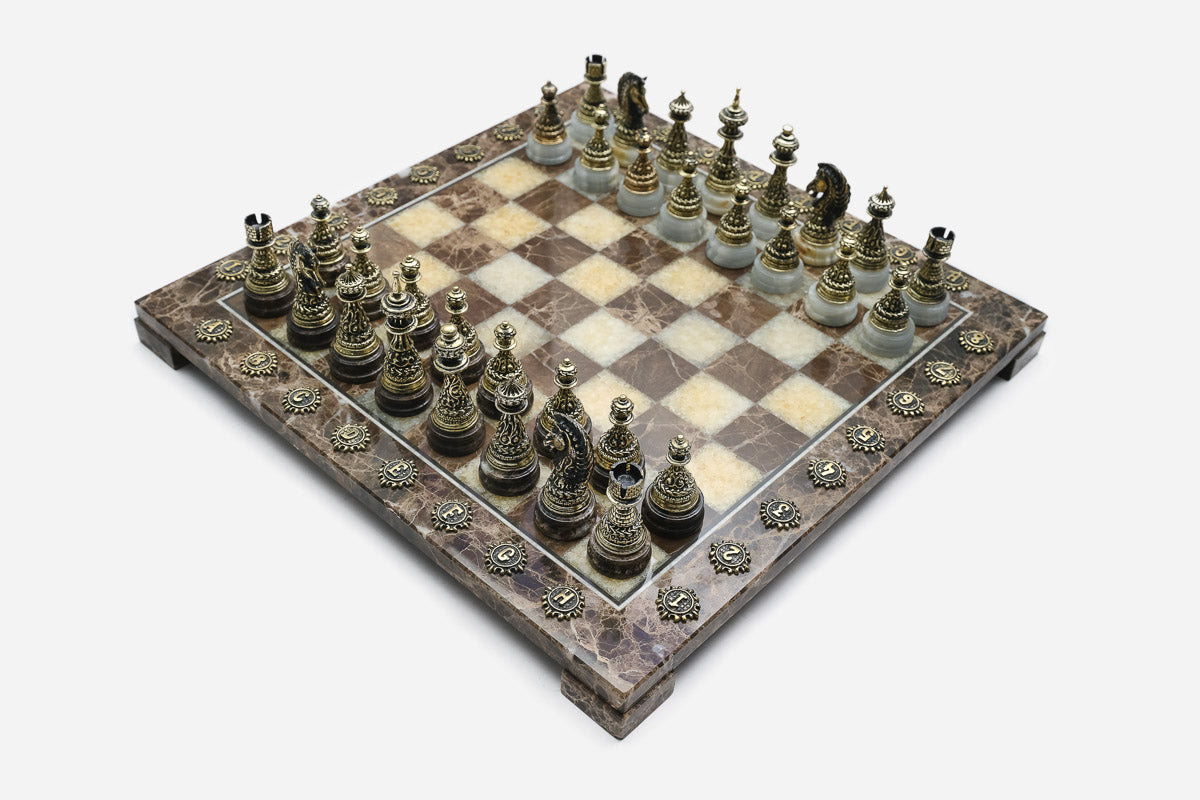Elevated view of the brown marble chess board with bronze pieces and brass coordinate medallions