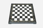 Top-down view of the empty black and white marble chess board with brass coordinate medallions