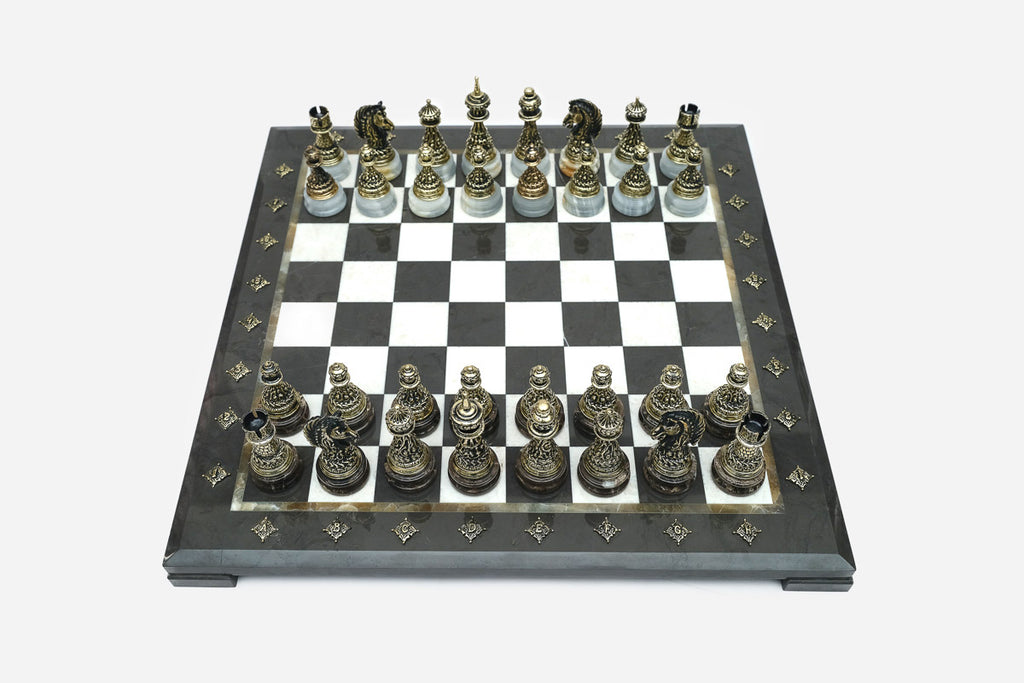 Elevated angle of the black marble chess board with bronze pieces and brass coordinate medallions