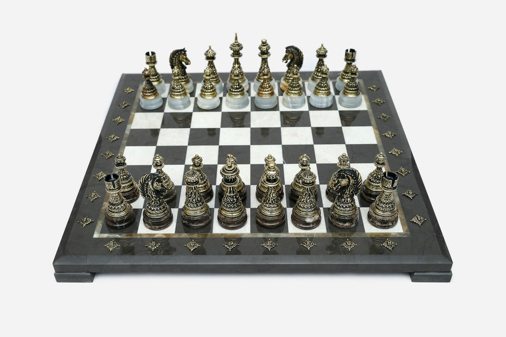 Black marble chess set with hand-cast bronze pieces arranged for play and brass coordinate medallions