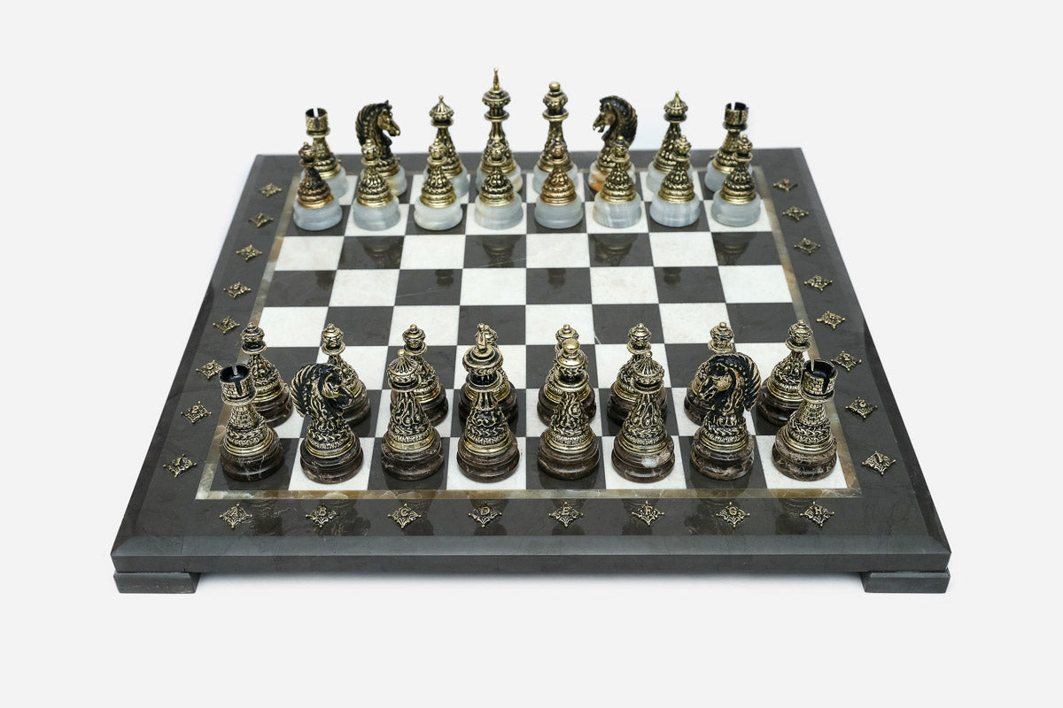 Black marble chess set with hand-cast bronze pieces arranged for play and brass coordinate medallions
