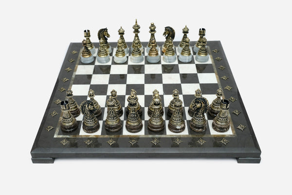 Black marble chess set with hand-cast bronze pieces arranged for play and brass coordinate medallions