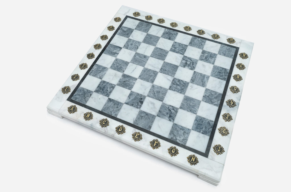 Angled view of the empty grey marble chess board with brass letter and number medallions