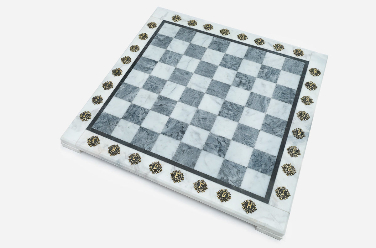 Angled view of the empty grey marble chess board with brass letter and number medallions