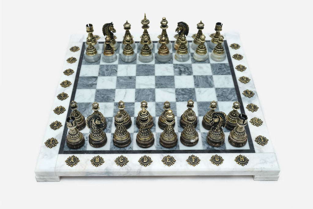 Grey and white marble chess set with hand-cast bronze pieces arranged for play and brass coordinate medallions