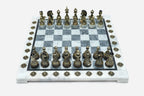 Grey and white marble chess set with hand-cast bronze pieces arranged for play and brass coordinate medallions