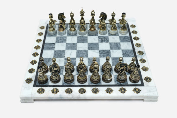 Grey and white marble chess set with hand-cast bronze pieces arranged for play and brass coordinate medallions