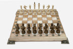 Chess board in pale wood with white marbled epoxy squares, brass corner brackets and wooden pieces set up for play