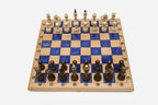 Compact folding chess board in pale wood with royal-blue epoxy squares and wooden pieces set up for play