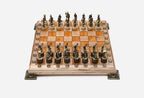 Chess board in pale wood with orange epoxy squares, brass corner brackets and figural bronze Greek-warrior pieces set up for play