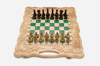Folding chess board in pale wood with green epoxy squares, carved grape-vine borders and wooden pieces set up for play