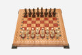 Folding chess board in pale wood with red epoxy squares, brass corner brackets and wooden pieces set up for play