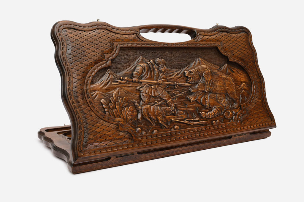 Carved beechwood backgammon board with a hunter-and-bear scene and a carry handle, propped open
