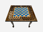 Standing chess table with a blue epoxy board and turned wooden pieces arranged around the border, on cabriole legs