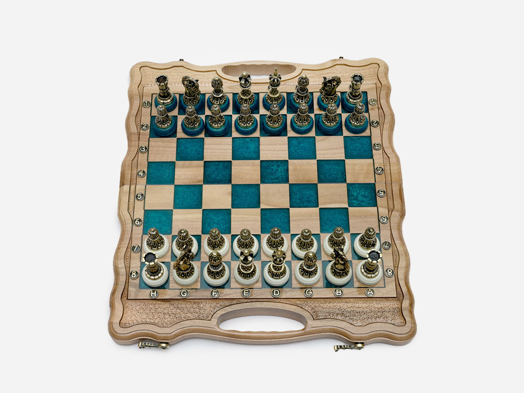 Folding chess board opened flat with turquoise-blue epoxy squares and ornate bronze figural chess pieces on white bases