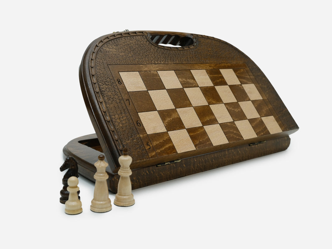 Round-topped folding chess and backgammon board standing open, showing the chess face and carry handle, with wooden pieces in front