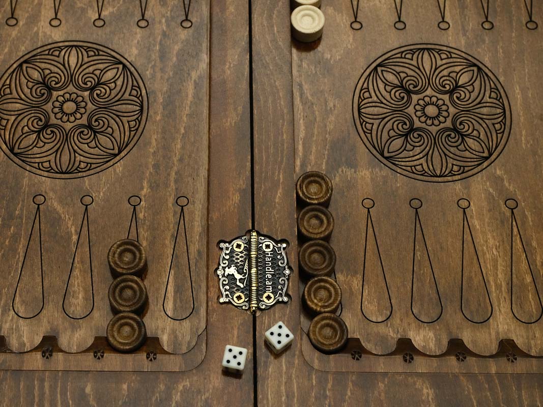 Close-up of the backgammon interior with carved rosette medallions, wooden checkers, dice and the brand medallion clasp