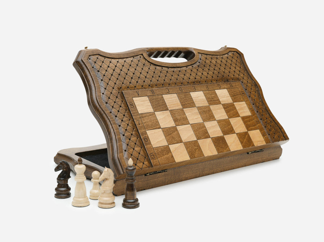 Folding Classic chess board standing open, showing the chessboard face, cross-hatch engraved border and carry-handle cutout, with wooden pieces in front