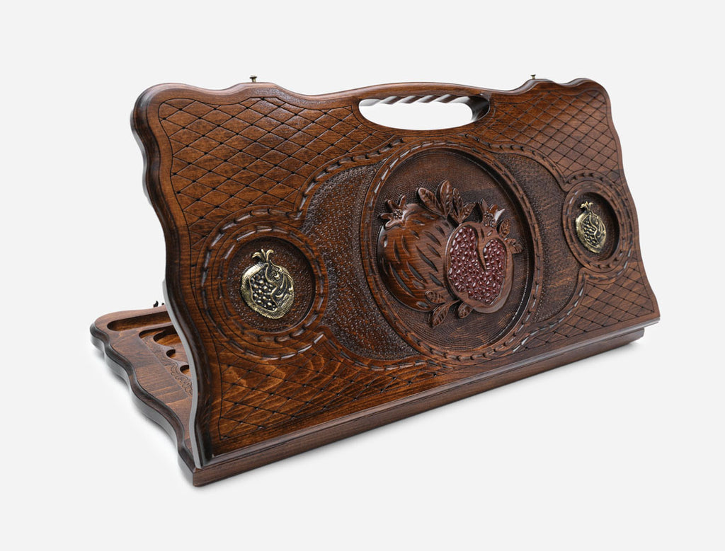 Carved beechwood backgammon board with a bronze pomegranate medallion and a carry handle, propped open