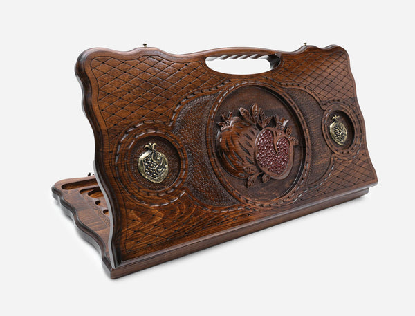 Carved beechwood backgammon board with a bronze pomegranate medallion and a carry handle, propped open