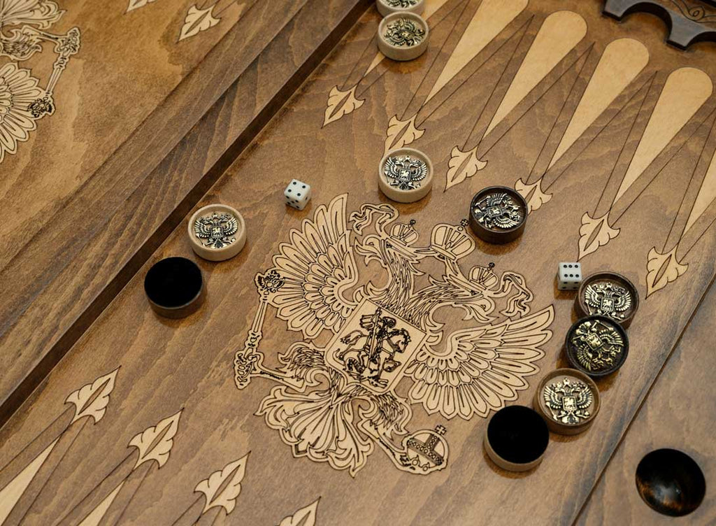 Close-up of the backgammon checkers, dice and cup on the Handle Russian Coat of Arms table